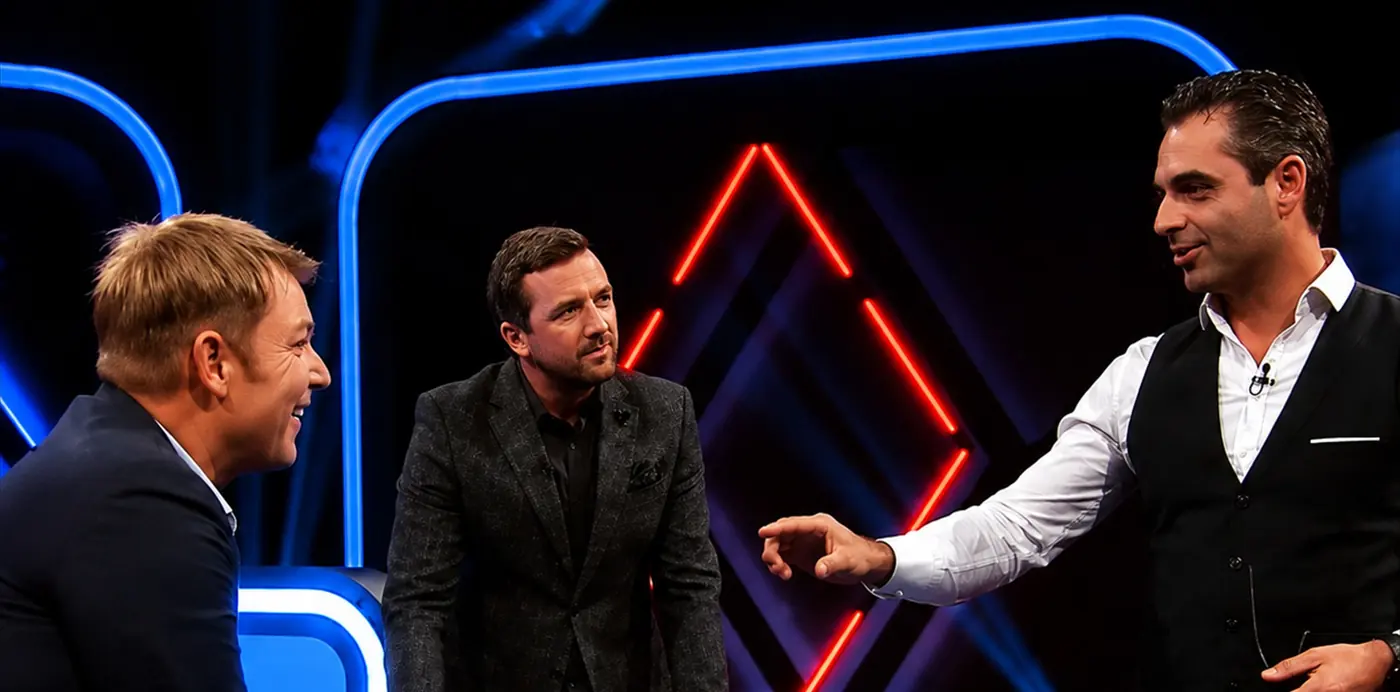 Phoenix reading a guest’s mind on a television set, giant ESP symbols glowing on the studio screen behind them